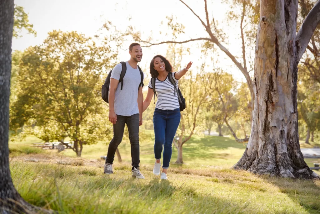 couple wearing backpacks hiking in park together utc